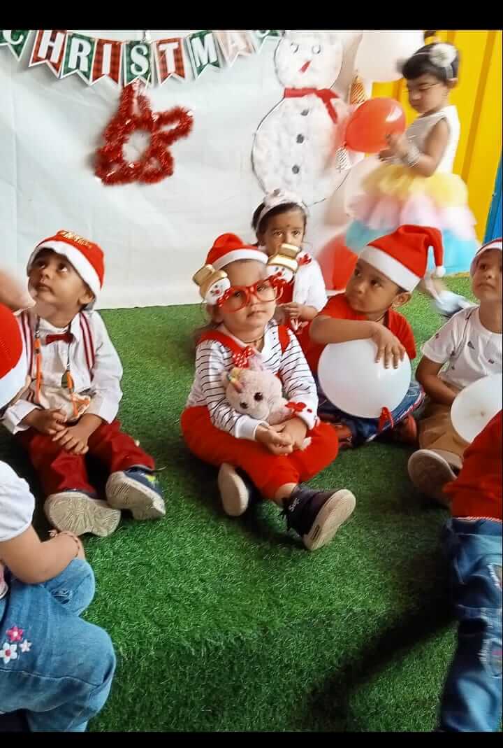Preschool children celebrating Christmas with decorations, gifts, and festive attire.